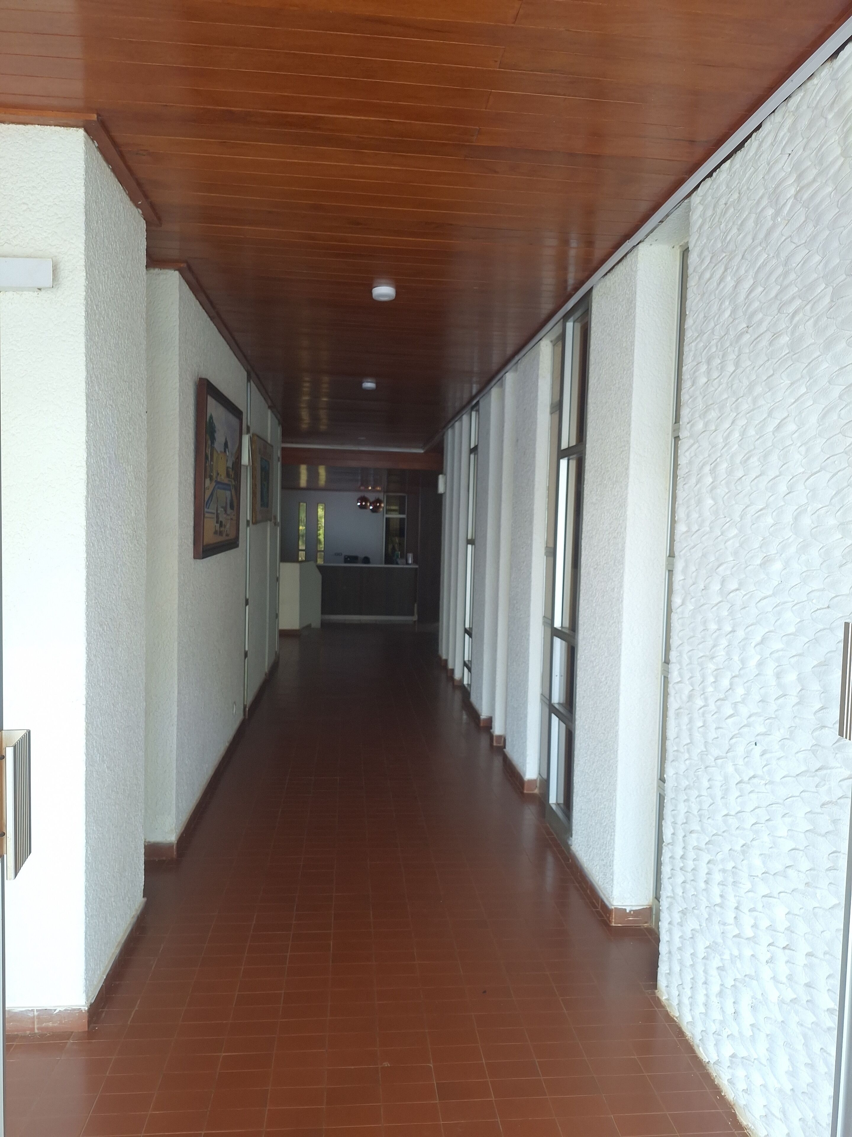 Un long couloir étroit avec un plafond en bois et des murs blancs.