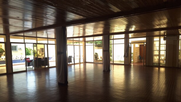 A spacious indoor area with large windows and wooden flooring. - Hôtel Les Frontières Odienné (Odienné)
