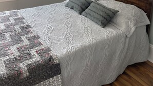 A bedroom with a large bed, a wooden headboard, a bedside lamp, and two framed pictures on the wall. - Dean's Seaside Escape,
Beautiful beaches and awesome sunrise and sunsets! (Cape Tormentine)