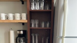 A kitchen with wooden cabinets, a white refrigerator, and various kitchenware including cups, plates, and a kettle. - Dean's Seaside Escape,
Beautiful beaches and awesome sunrise and sunsets! (Cape Tormentine)