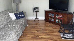 A bedroom with a bed, a TV, a radio, and a bookshelf.