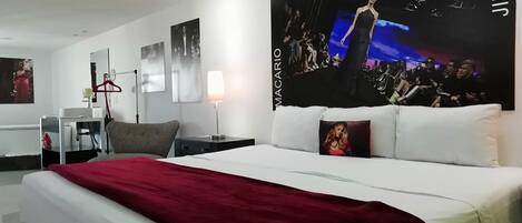 Una habitación de hotel con una cama grande, un escritorio, una silla, una lámpara y un cartel en la pared.