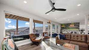 Un vaste espace de vie doté d’une grande fenêtre, d’un ventilateur de plafond et offrant une vue sur l’extérieur.