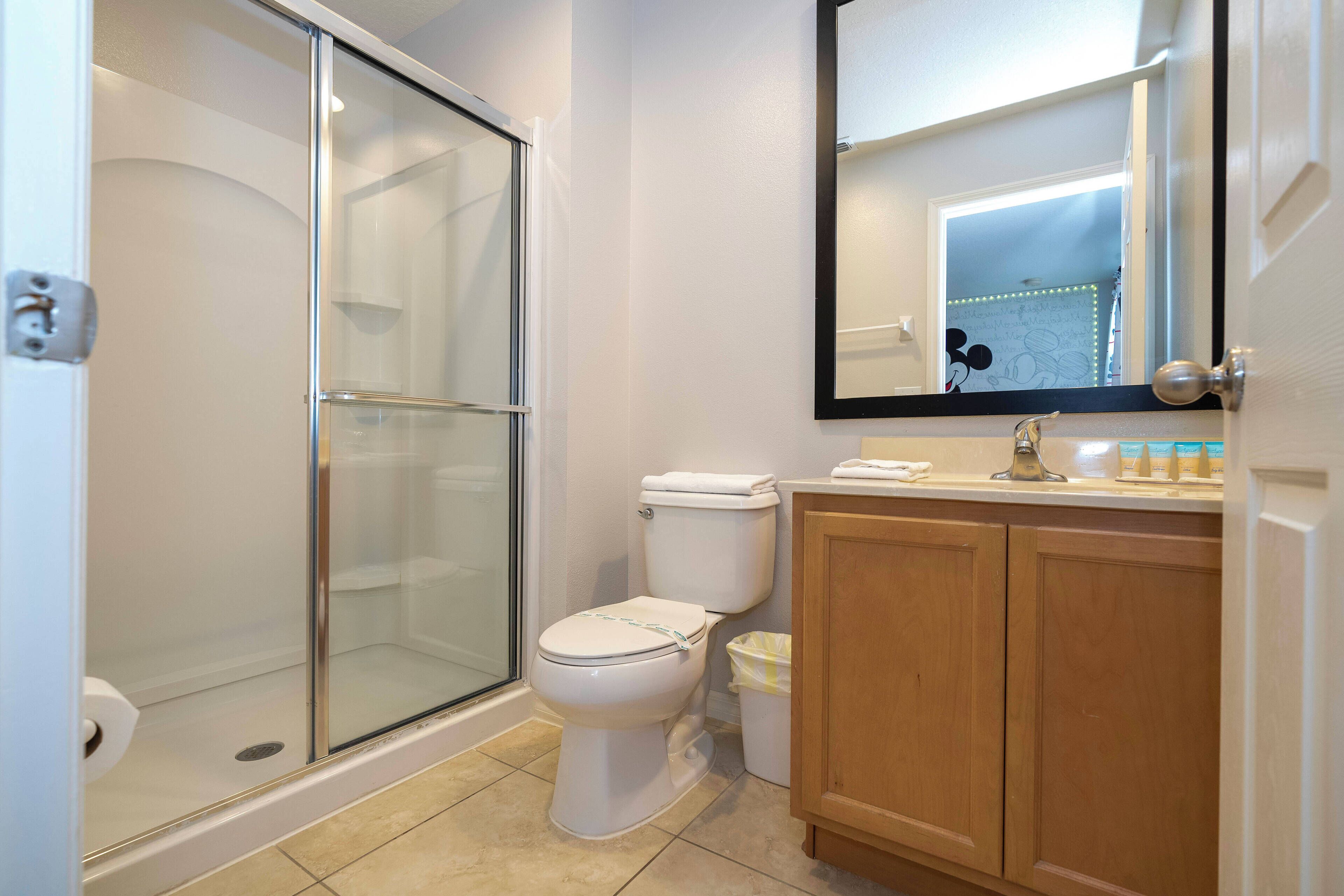 A bathroom with a glass-enclosed shower, a toilet, and wooden cabinets.