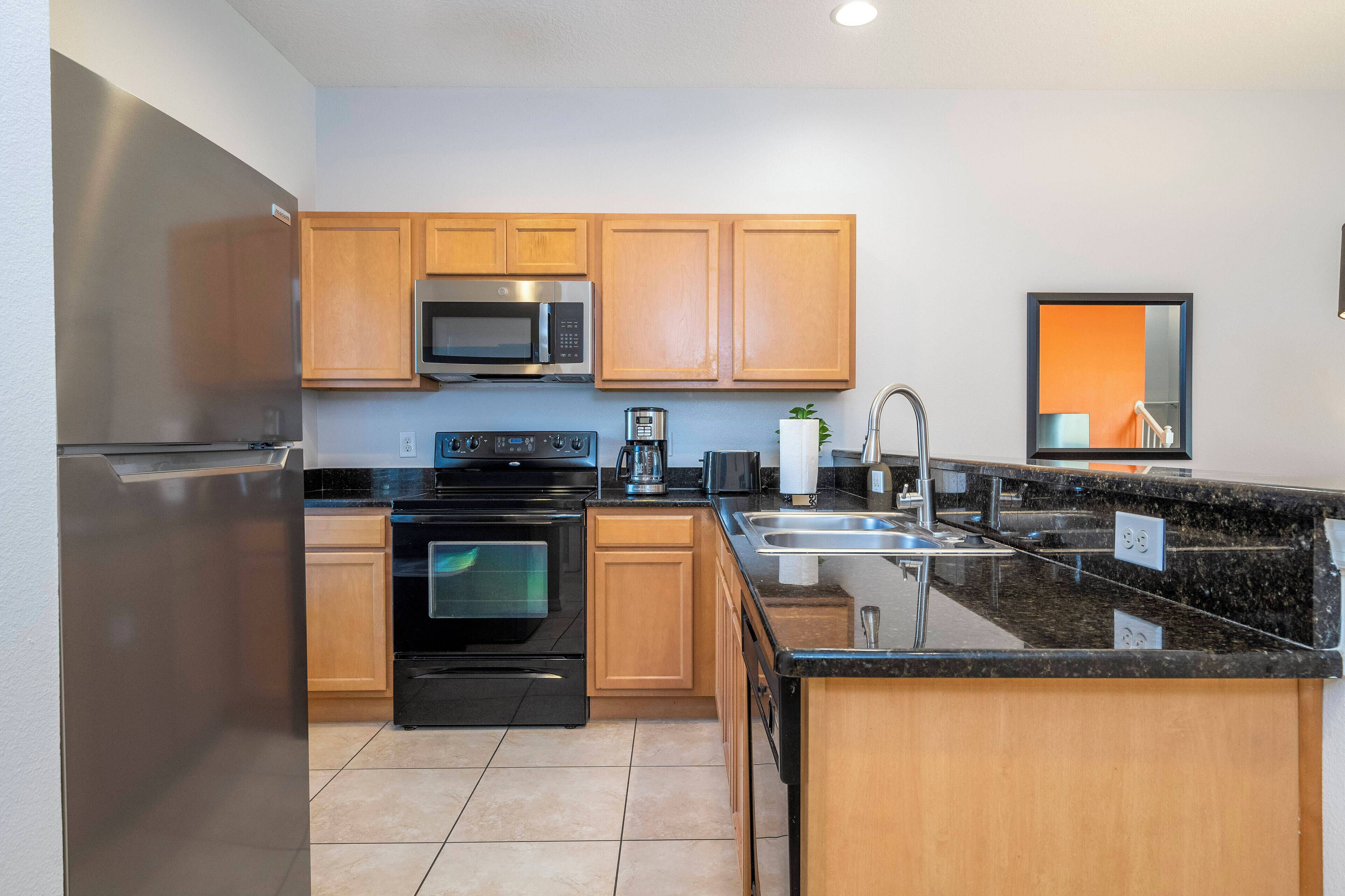A modern kitchen with stainless steel appliances, wooden cabinets, and a granite countertop.