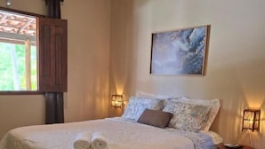 A neatly made bed with a white duvet, two rolled towels, and a blue striped rug on a tiled floor. - Recanto Verde (Mata de Sao Joao)