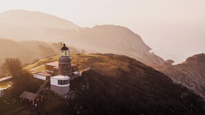 A lighthouse on a cliff overlooking the sea, with a small building nearby. - Falknästet unique accommodation in one of Sweden's most spectacular natural areas. (Höganäs)