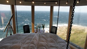 A bed with a view of the ocean, a telescope, and a table with candles. - Falknästet unique accommodation in one of Sweden's most spectacular natural areas. (Höganäs)