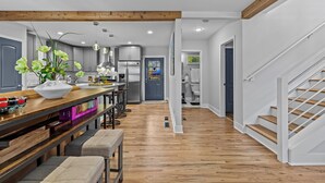 A modern kitchen with wooden flooring, a central island, and stainless steel appliances.