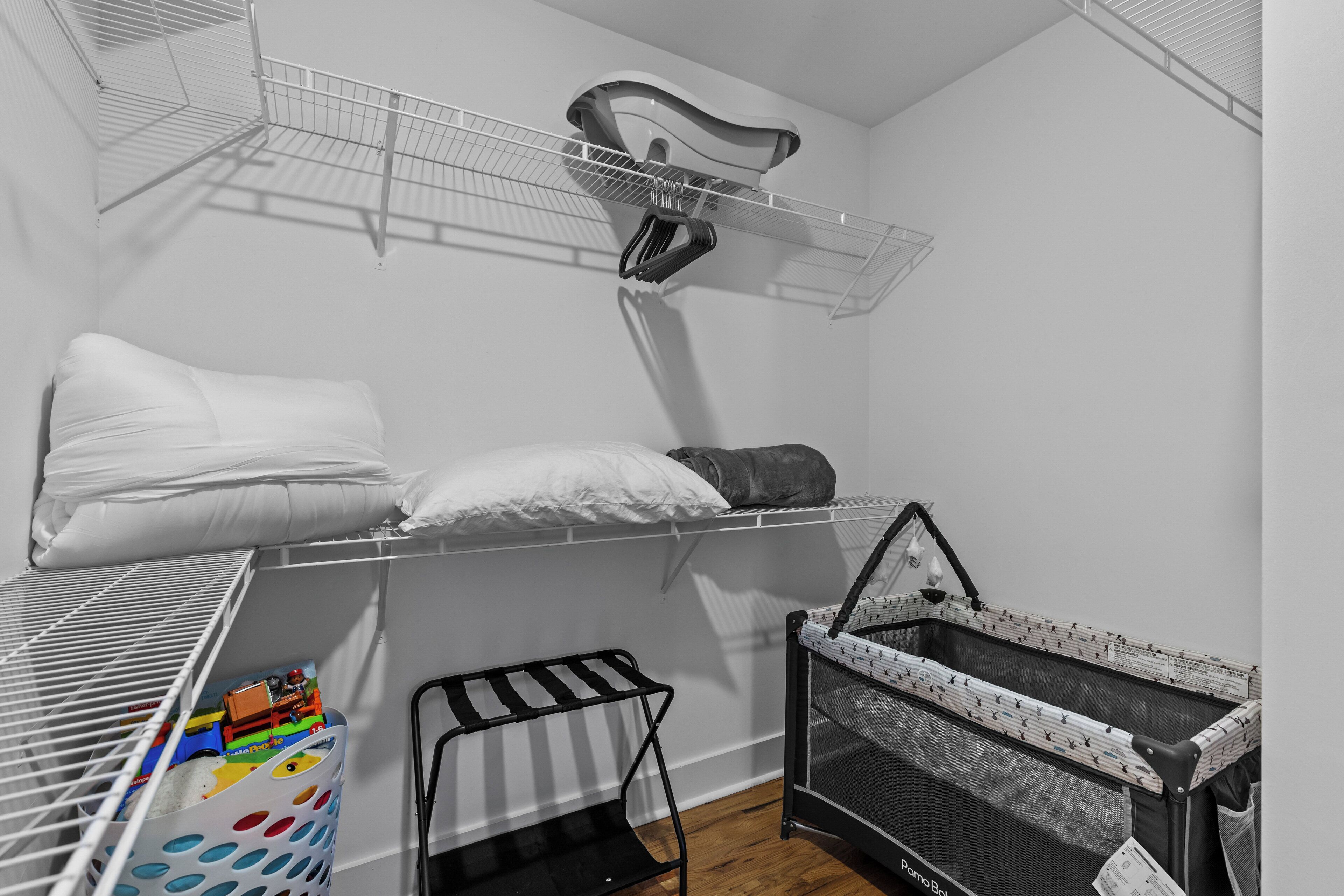 A compact room with a bunk bed, a small crib, and a drying rack.