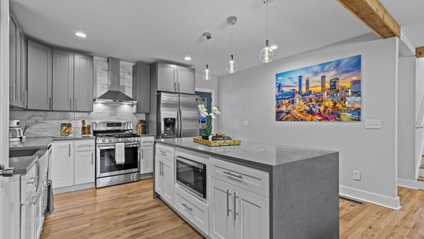 A modern kitchen with grey cabinetry, stainless steel appliances, and a large island.