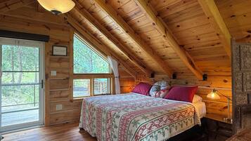 Een slaapkamer in een houten chalet, met een bed, een raam en een plafondlamp.