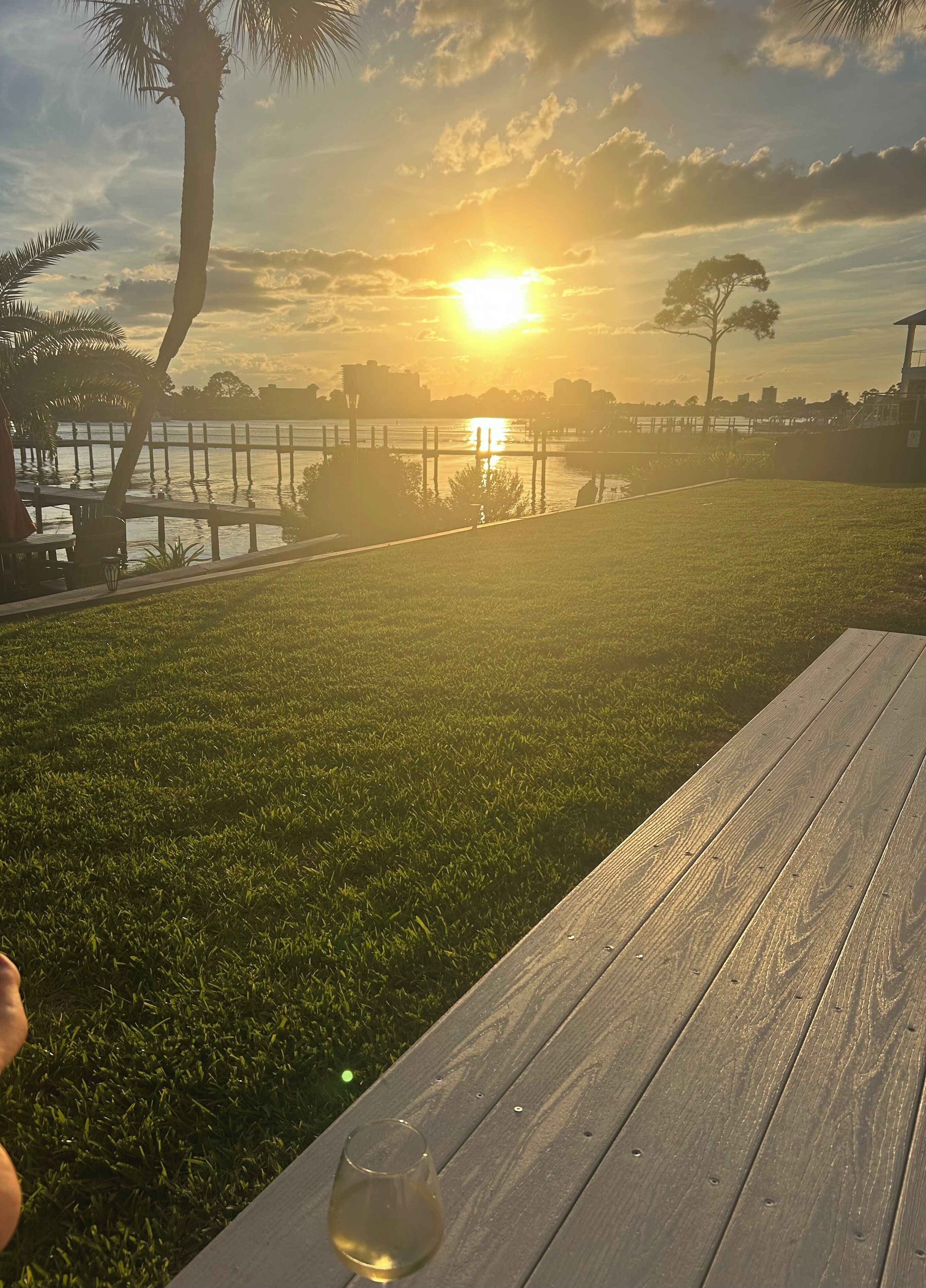 A sunset view from a wooden deck overlooking a body of water with a distant city skyline.