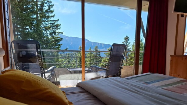 A room with a bed, two chairs, and a view of trees and mountains. - V du Bachat Epicea B Ndeg22 - 3P6 (Chamrousse)