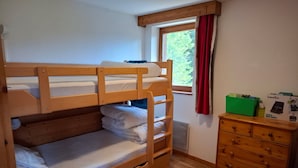 A bunk bed room with a wooden dresser and a window with red curtains. - V du Bachat Epicea B Ndeg22 - 3P6 (Chamrousse)