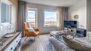 Ein Wohnzimmer mit großem Fenster, Fernseher, Kamin und Sofa.