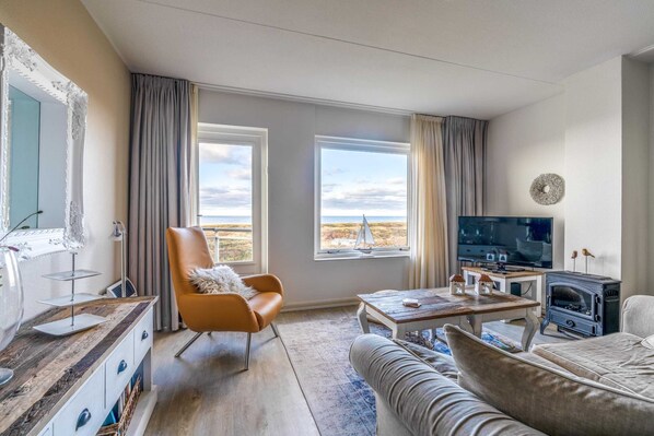Ein Wohnzimmer mit großem Fenster, Fernseher, Kamin und Sofa.