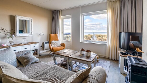 Ein gemütliches Wohnzimmer mit Sofa, Sessel, Couchtisch, Fernseher und Kamin.