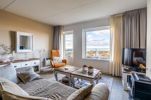 Un salon confortable avec un canapé, un fauteuil et une table basse, une télévision et une cheminée.