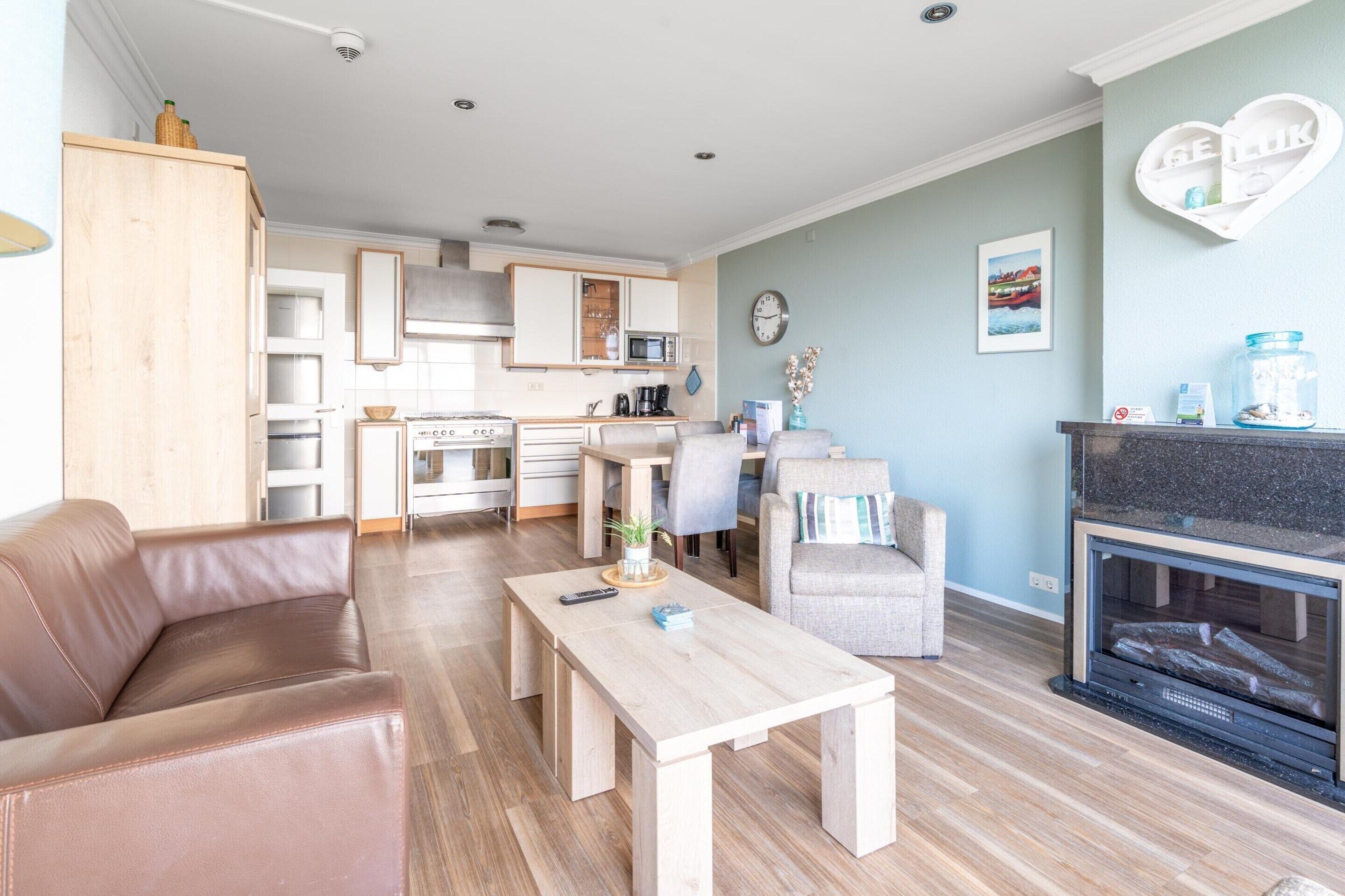Una sala de estar moderna con un sofá de cuero marrón, una mesa de centro de madera y una chimenea.