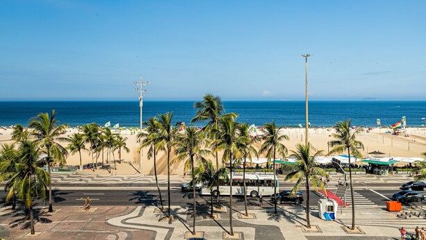Une vue sur la plage, avec des palmiers, un autobus et une plage en arrière-plan.
