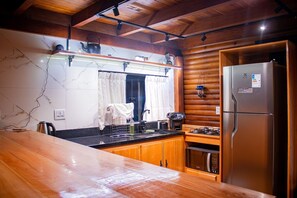 Une cuisine dotée de meubles en bois, d’un réfrigérateur en acier inoxydable, d’une cuisinière à gaz et d’un dosseret en marbre.