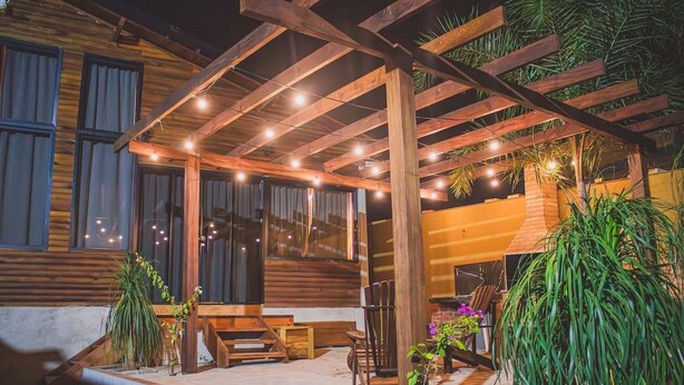 Una cabaña de madera con porche cubierto, mobiliario exterior y macetas con plantas.