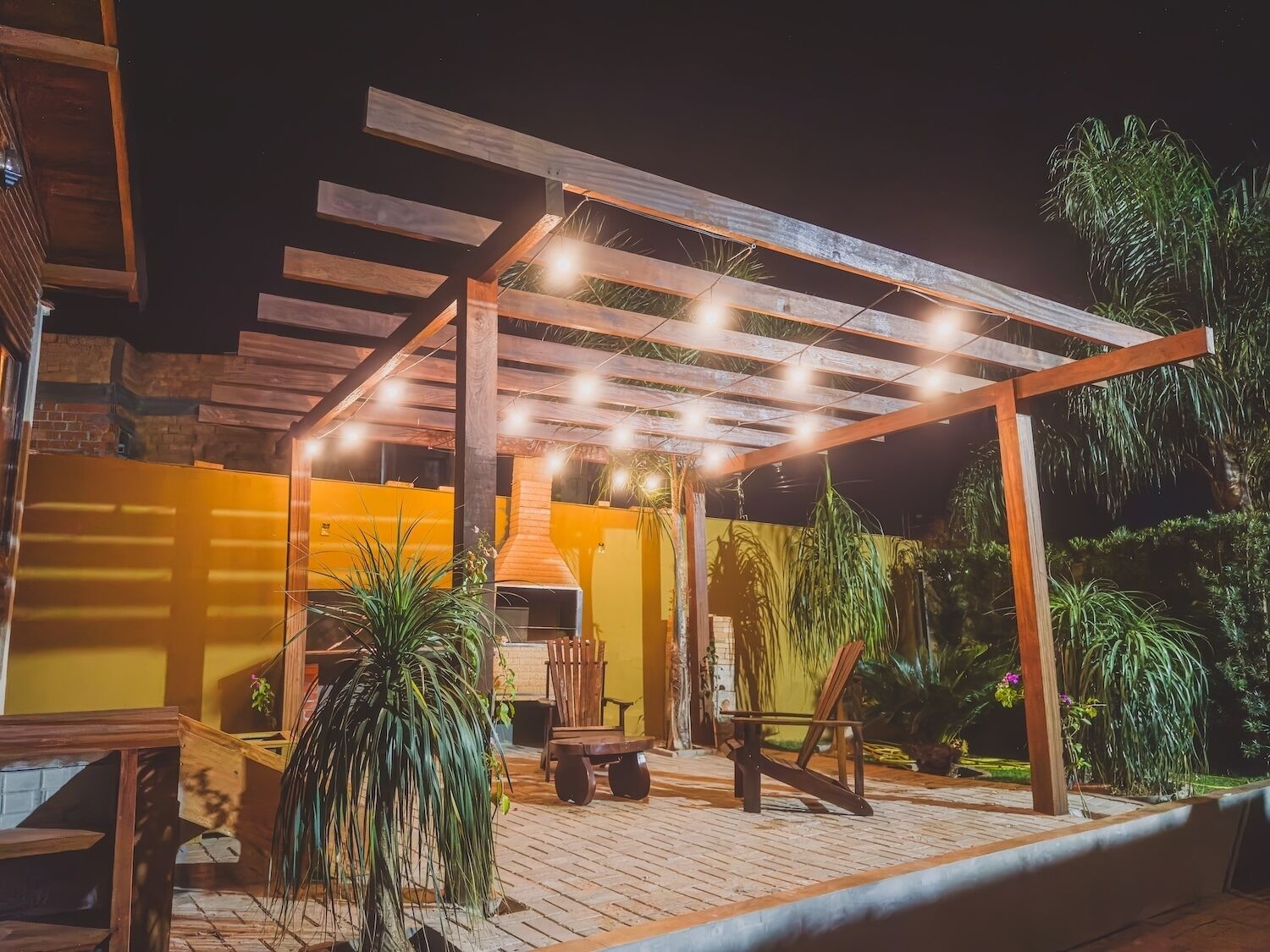 Ein Patio im Freien mit einer Pergola, Sitzgelegenheiten und einem Grill.