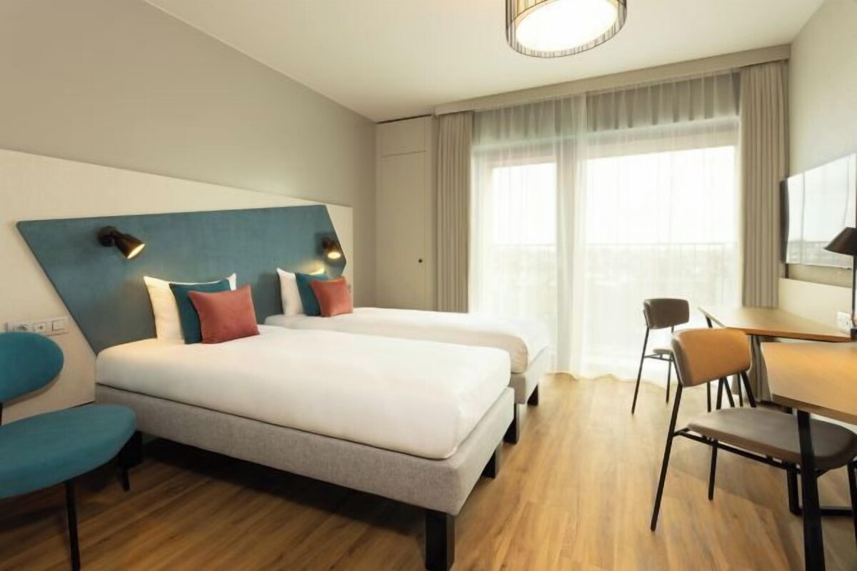 Ein Hotelzimmer mit zwei Betten, einem Schreibtisch und einem Stuhl.