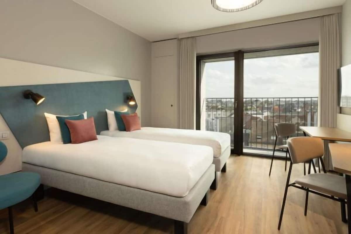 Habitació d'hotel amb un llit gran, una taula de treball i vistes a la ciutat.
