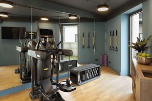 Une salle de sport équipée de matériel d’exercice, d’un miroir et d’une fenêtre.