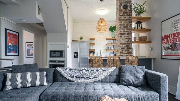 Ein Wohnzimmer mit grauem Sofa, einem Couchtisch und einer Pendelleuchte.