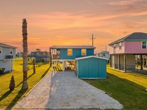Zona residencial con casas, camino de grava y un cobertizo pequeño.