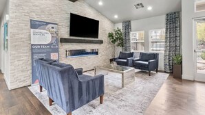 A modern living room with a fireplace, two sofas, a coffee table, and a TV mounted on the wall.