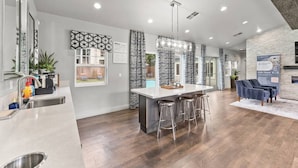 A modern kitchen with a central island, bar stools, and a dining area with a fireplace.