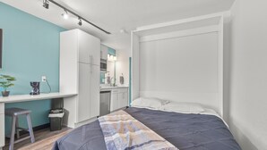Een moderne slaapkamer met een bed, bureau en kitchenette.