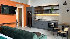 A modern kitchen with grey cabinets, a built-in oven, and a dining area with two chairs. - Heritage X (São Paulo)