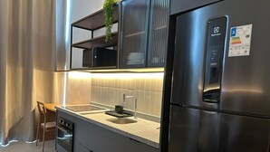 A modern kitchen with a stainless steel refrigerator, a built-in oven, a sink, and a small countertop. - Heritage X (São Paulo)