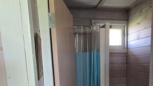 A small, compact bathroom with a toilet, a sink, and a shower curtain. - Suite 9 - Older/Simple/Rustic/No Frills/Budget 1 Bed - Near Cabot Beach Park (Kensington)