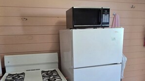 A kitchen with a white stove, a white refrigerator, and a microwave on top of the fridge. - Suite 9 - Older/Simple/Rustic/No Frills/Budget 1 Bed - Near Cabot Beach Park (Kensington)