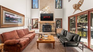 Ein Wohnzimmer mit Kamin, einem Netflix-Schild und einem Balkon mit Gartenmöbeln.