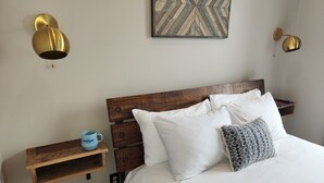 A neatly arranged bedroom with a wooden headboard, a bedside table with a mug, and a wall-mounted light fixture. - 2nd Street Loft - Riverview (Washington)