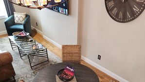 A dining area with a round table, wicker chairs, a glass coffee table, and a wall-mounted clock. - 2nd Street Loft - Riverview (Washington)