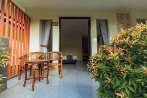 A room with a sofa, a dining table with chairs, a wooden partition, and a large potted plant. - Semaya One Beach Hotel (Bali)