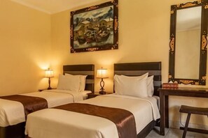 A hotel room with two beds, bedside lamps, a desk with a chair, and a large mirror. - Semaya One Beach Hotel (Bali)