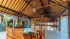 A spacious covered area with wooden furniture, a bar, and a view of the surrounding area. - Semaya One Beach Hotel (Bali)