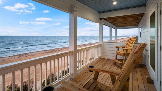 Eine Holzterrasse mit Blick auf Strand und Meer.