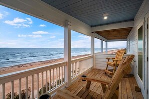 Una terraza de madera con vista a la playa y el océano.