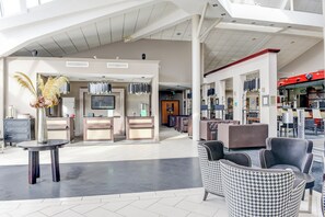 Un hall d’entrée spacieux comprenant un comptoir d’accueil, un espace détente et une partie réservée au restaurant.