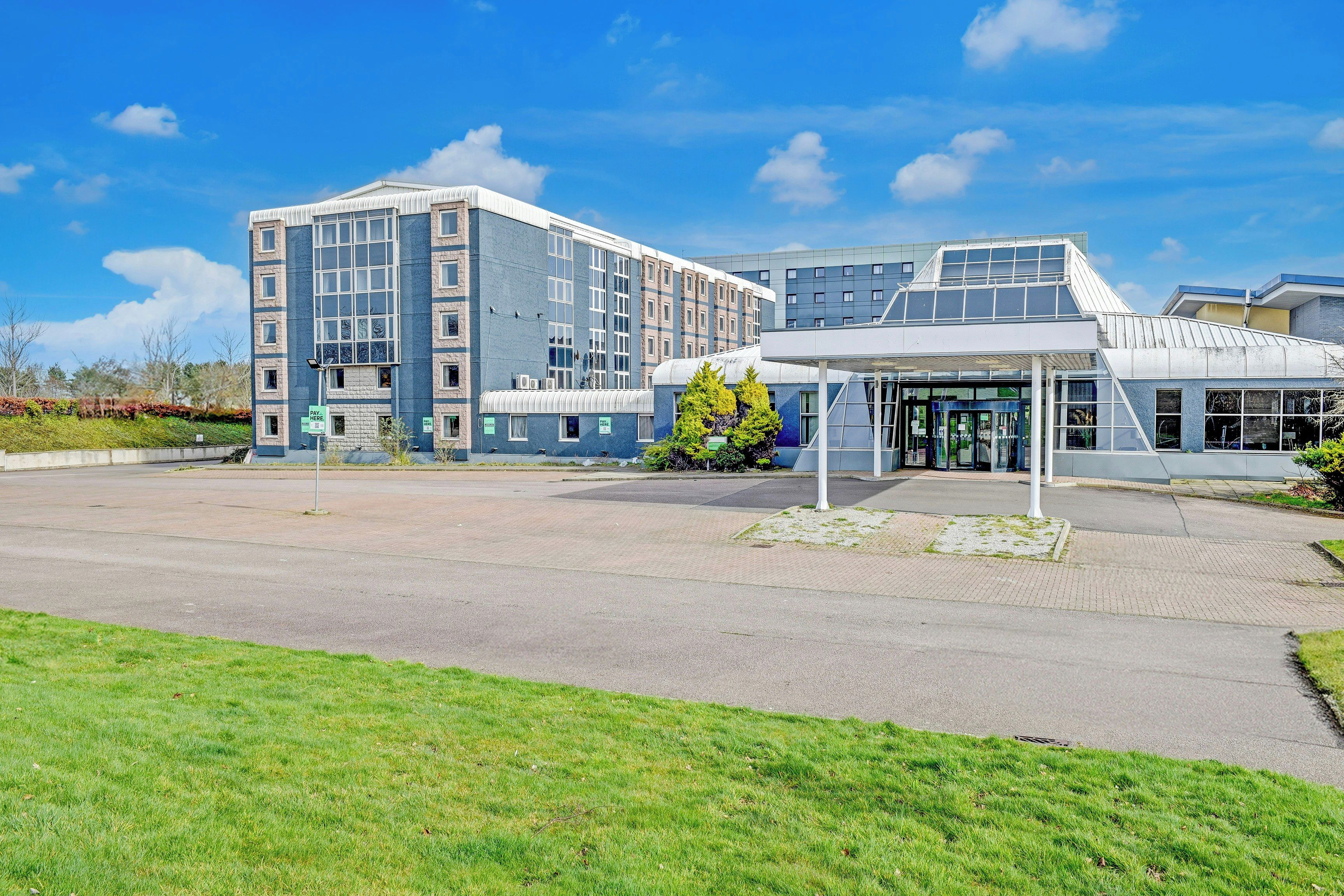 A modern building with a covered entrance and a parking area.